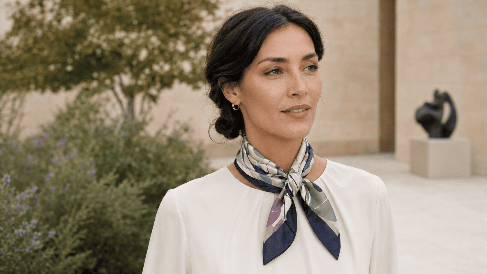 Woman wearing a medium square silk scarf tied neatly at the neck