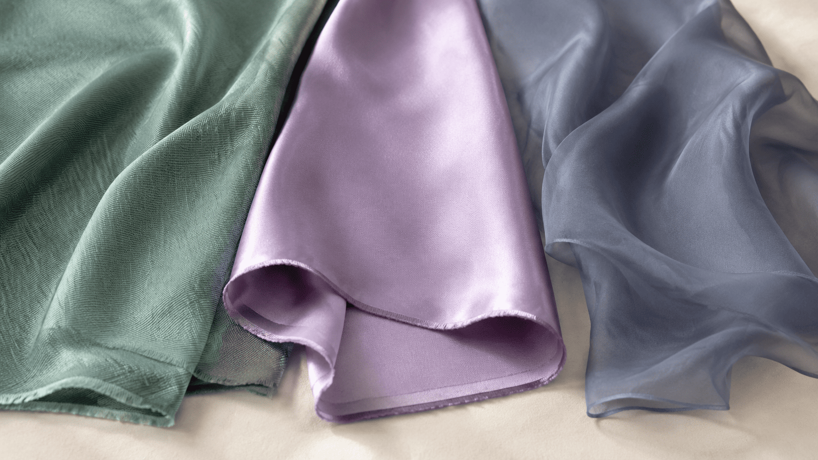 Silk scarf stored loosely with acid-free tissue in a breathable box beside a smooth padded hanger
